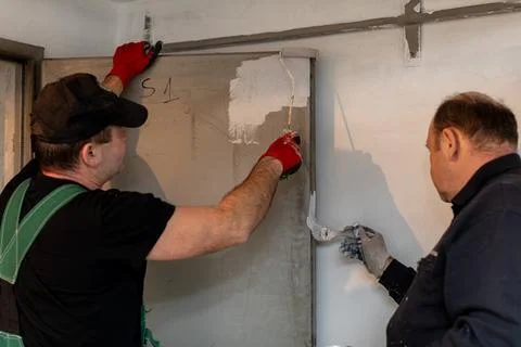 Workers are actively applying fresh paint meticulously on the wall for an Stock-Fotos