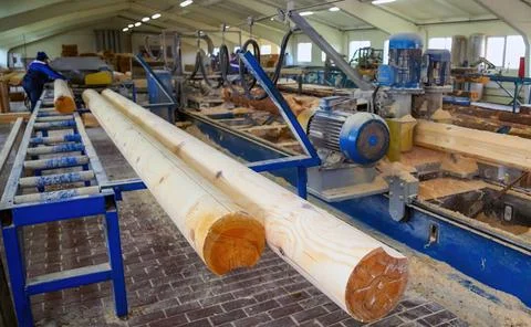 Workers are actively cutting large logs into planks at a lumber mill, highlig Stock Photos