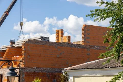 Workers are assembling a brick wall at a construction site, with a crane li.. 库存照片