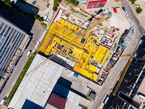 Workers are building a new structure at a construction site. Cranes are lifti Stock Photos