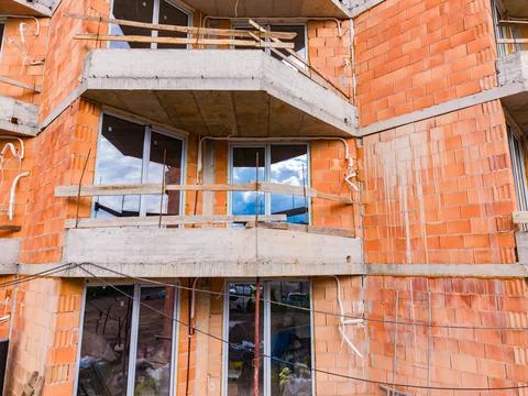 Workers are building a structure with brick walls and concrete balconies. The Stock Photos