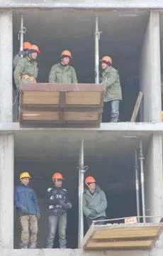 Workers are on building structures, repair the wall of the building. Stock Photos
