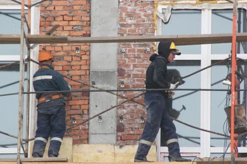 Workers are on building structures, repair the wall of the building. Stock Photos