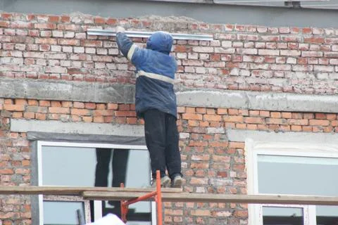 Workers are on building structures, repair the wall of the building. Stock Photos