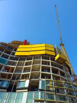 Workers are building a tall structure with cranes and scaffolding. Constructi Stock Photos