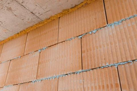 Workers are building a wall using orange bricks. The gaps between the bricks  Stock Photos