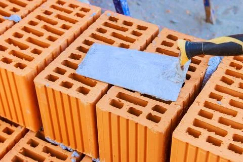 Workers are building wall using orange bricks, mortar on construction site Stock Photos