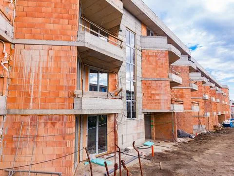 Workers are busy completing a new building project. The structure shows raw b Stock Photos