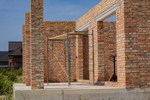 Workers are constructing a brick building in a residential neighborhood und.. Stock Photos