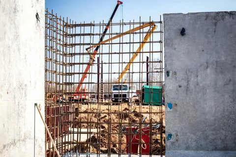 Workers are constructing a building at a construction site, with cranes lifti Stock Photos