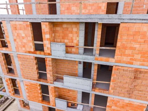 Workers are constructing a building using red bricks and concrete materials.  Stock Photos