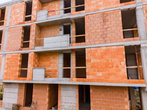 Workers are constructing a building using orange bricks and concrete. The str Stock Photos
