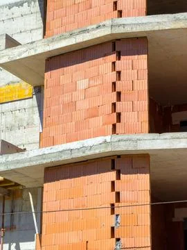 Workers are constructing a building using orange bricks and concrete. The str Foto stock