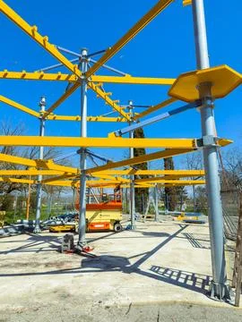 Workers are constructing a framework using yellow beams and poles. Cranes and 库存照片
