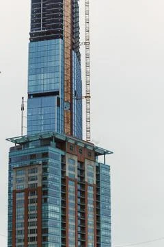 Workers are constructing a high-rise building in an urban area while cranes a Stockfoto's
