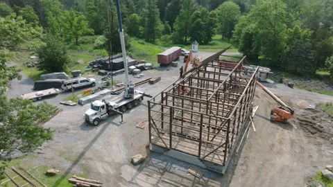 Workers are constructing a large wooden Barn in a forest area. Cranes are Stockbeeldmateriaal 331270451