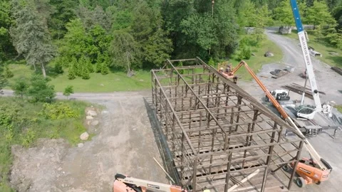 Workers are constructing a large wooden barn structure in a forest area. Cranes Stock Footage 331270789