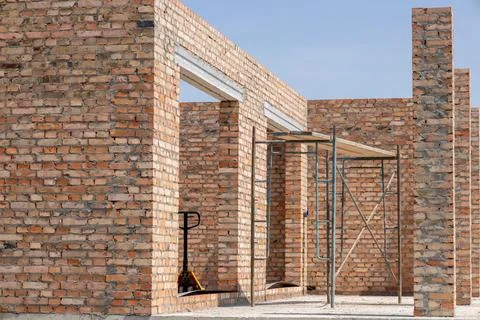 Workers are constructing a new building with brick walls and scaffolding in.. Stock-Fotos