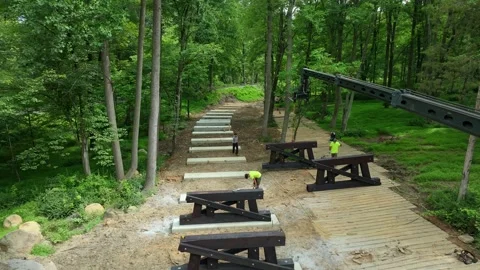 Workers are constructing a walking path in a forest. They lay wooden beams and Stock Footage 338058665