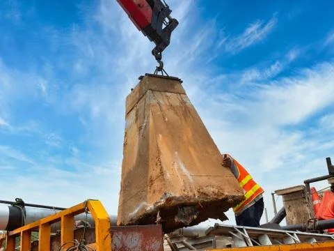 Workers are controlling the direction of the foundation pillar that is lifted Foto stock