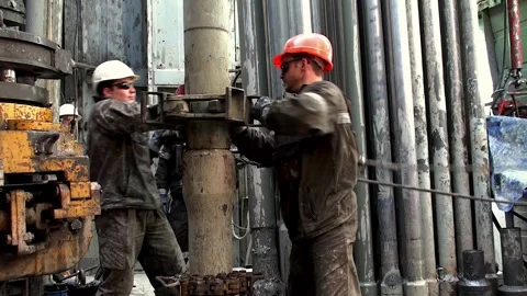 Workers are controlling the drill string  lengthening at the wellhead. Stock Footage 259798227