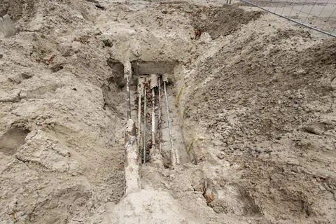 Workers are digging at a construction site, revealing underground pipes and u Photos