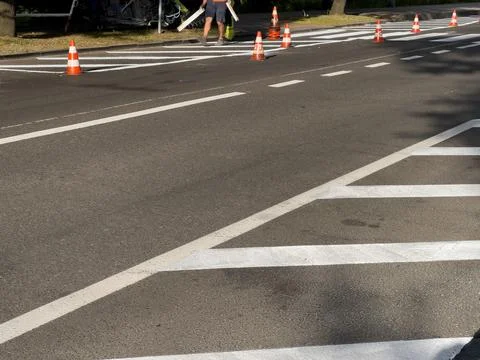 Workers are diligently painting new road markings on a bustling street, enh.. Stock Photos