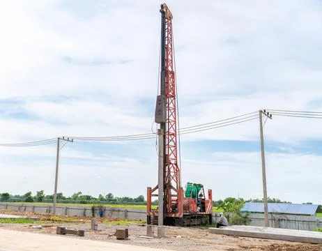 The workers are driving piles at the construction site. Stock Photos