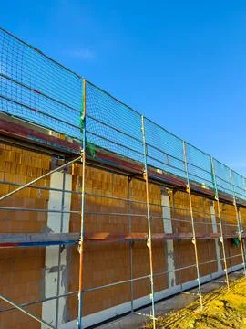 Workers are engaged in constructing a wall at a building site, with scaffoldi 스톡 사진