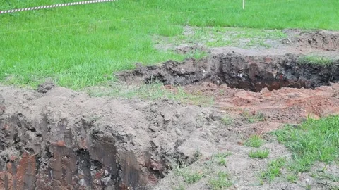 Workers are engaged in excavation, digging a large trench in an open field. The 스톡 동영상 339004614
