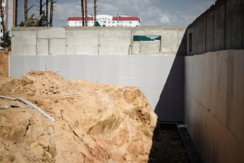 Workers are engaged in foundation work at a construction site surrounded by s Stock Photos