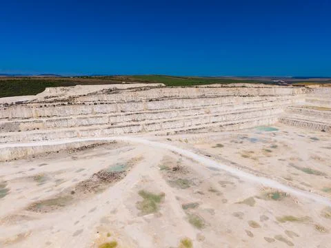 Workers are extracting materials from a large quarry with visible layers of r Stock Photos