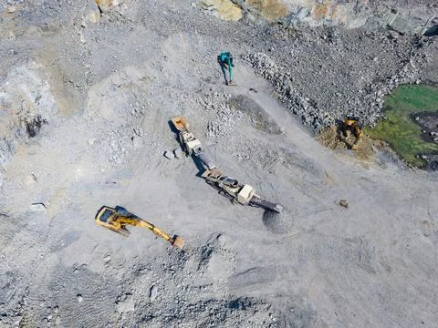 Workers are in a granite quarry using various machines for mining and extract Stockfoto's