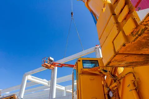 Workers are helping crane to keep balance and direction of concrete joist Stock Photos