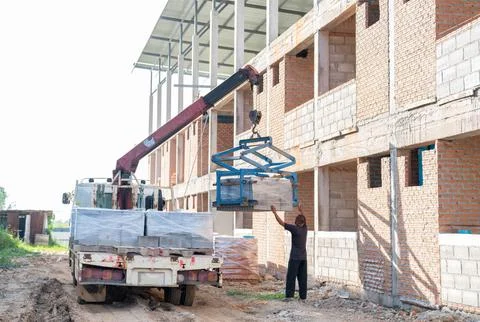 Workers are helping mobile crane to manage concrete block. Stock Photos