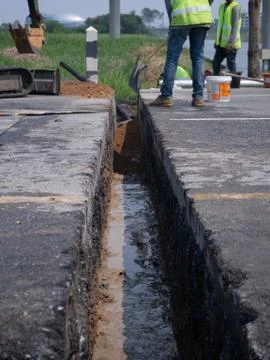 Workers are installing concrete drains on the side of the road Stock Photos