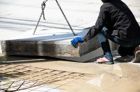 Workers are installing a large concrete manhole cover. Stock Photos