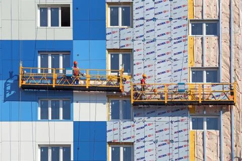 Workers are installing panels on the facade of a multi-storey building 스톡 사진