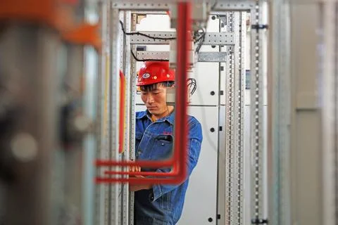 The workers are installing the power compensation cabinet in the workshop. Stock Photos