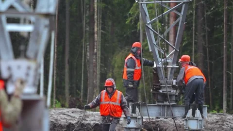 Workers are installing a power transmission tower in harsh conditions, erecting Stock Footage 263539509