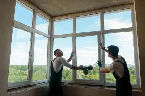 Workers are installing a window. Two men mounting a sash into the frame Stock Photos