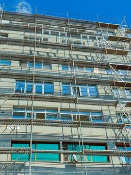 Workers are installing windows on a tall building with scaffolding. The sun s Stock Photos