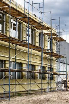 Workers are insulating the facade of a building with mineral wool while using Stock Photos