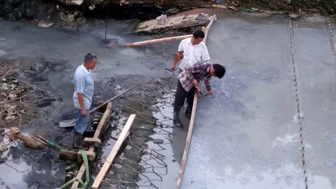 The workers are laying cement in the river channel for construction Stock Footage 81013998