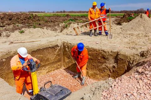 Workers are level foundation using vibration plate compactor and rake Stock Photos