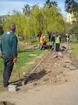 Workers are making a pedestrian path. Lay tiles and edges. The men work as .. Stock Photos