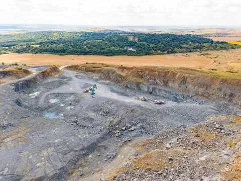 Workers are performing tasks at a granite quarry. Heavy machinery is present  Stock Photos