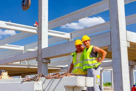 Workers are posing at work, attaching crane hooks to concrete joist in truck Stock Photos