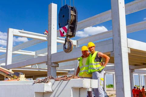 Workers are posing at work, attaching crane hooks to concrete joist in truck Stock Photos