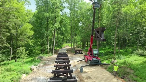 Workers are preparing to build a bridge in a forest area. Crane lifts large Video stock 338058082